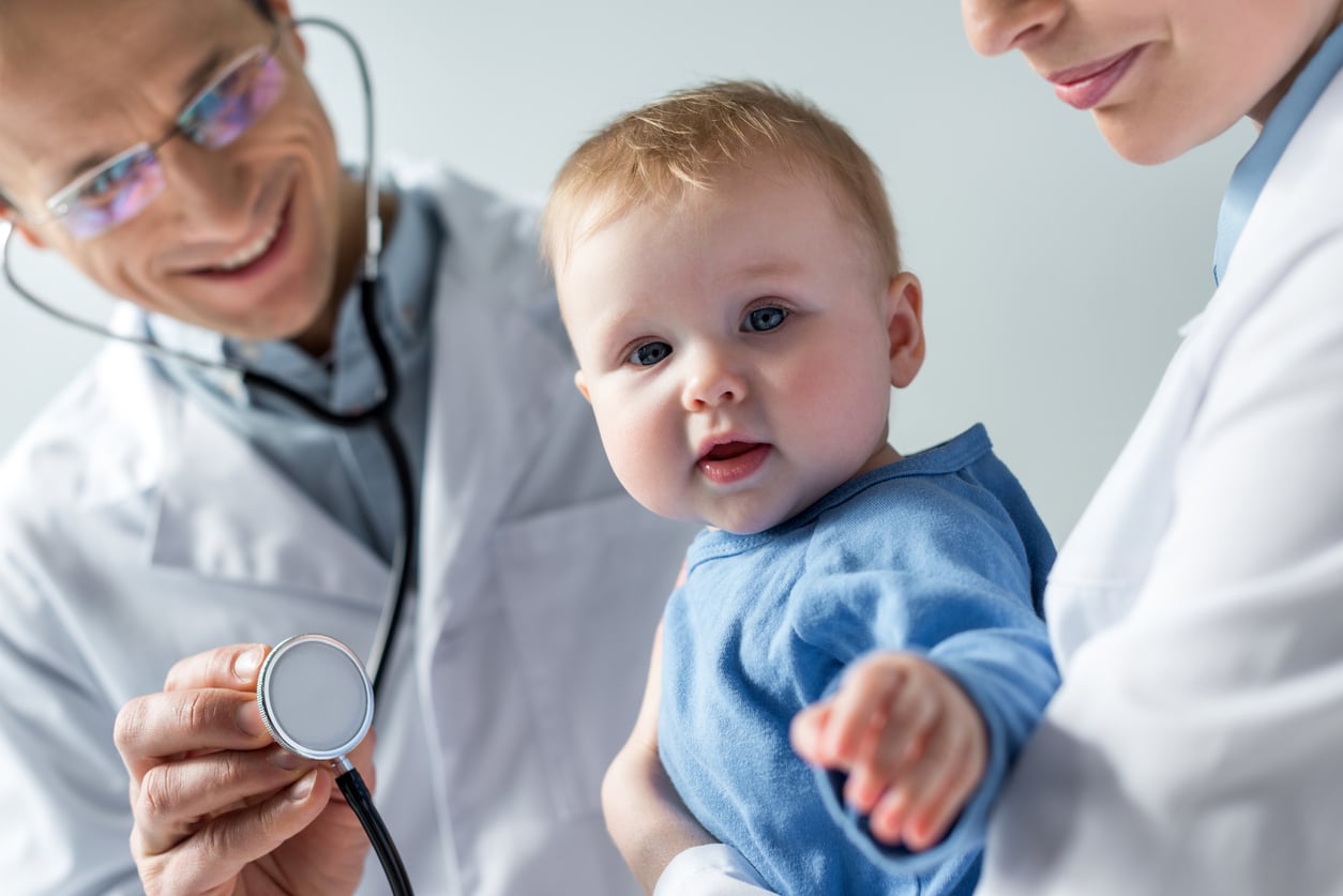 cropped shot of pediatricians checking breath of adorable little baby