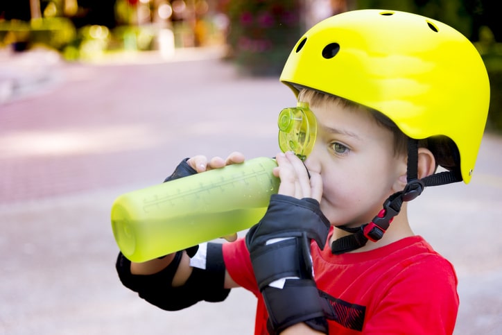 Child with roller skate helmet, drink a water.