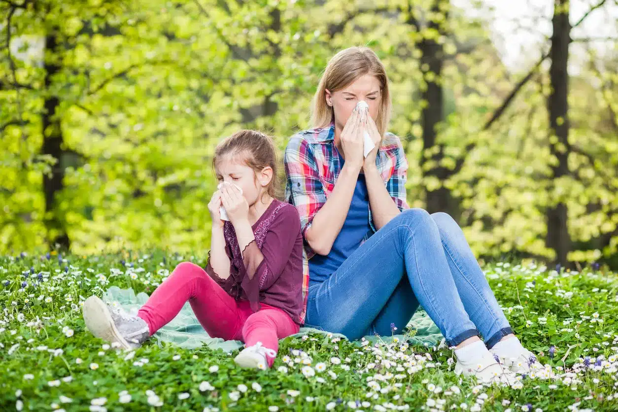 Seasonal Allergies Mother and daughter blow their noses on a beautiful, pollen-filled spring day.