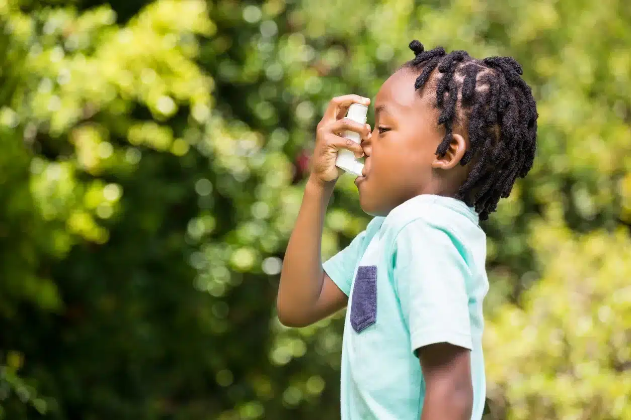 Boy using an asthma inhaler Boy using an asthma inhaler in the park