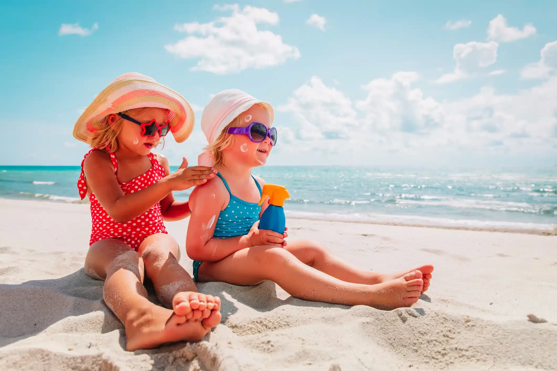sun protection, cute girls with sun cream at beach